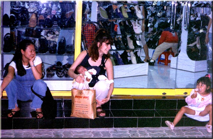 Sharon and Jocelyn talking to a little girl outside a shoe store in Saigon